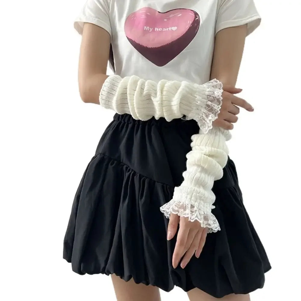 A person is wearing white fingerless arm warmers and a black skirt, with a white t-shirt featuring a pink heart design.