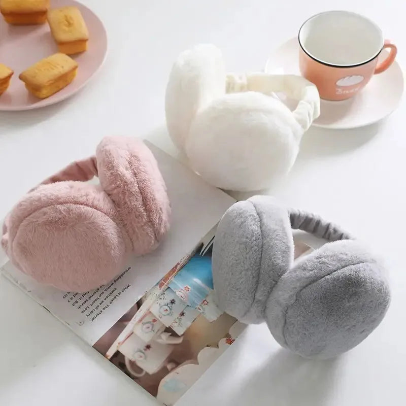 A collection of soft pink and gray plush fur ear warmers or earmuffs displayed on a white surface.