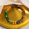 A bracelet made of tumbled citrine and tiger's eye stones displayed on a golden plate.