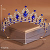 A sparkling crystal baroque bridal tiara headpiece featuring blue gemstones and gold-toned metal.