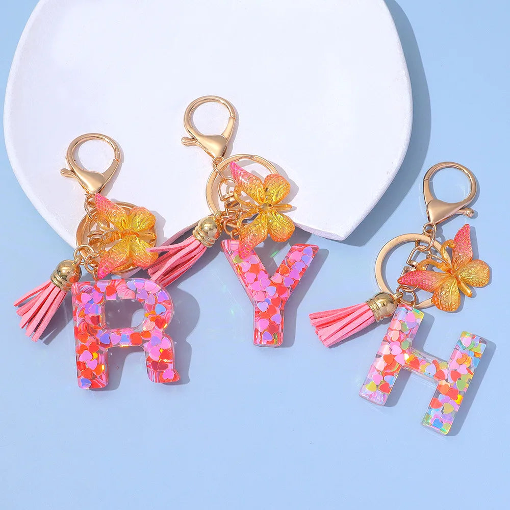 Alphabet letter acrylic keychain featuring a pink butterfly and pink tassel