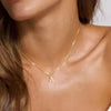 A gold plated alphabet initial necklace worn around the neck of a woman.