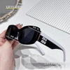 A pair of black MU sunglasses with white accents is being held, set against a white background.