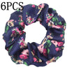 Un set de seis gomas de tela satinada azul oscuro con estampado floral para el cabello