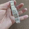 Eine Hand hält ein Vintage-Silber-Totenkopf-Armband als Anhänger für Männer, mit detaillierter Gravur und Gliederkonstruktion