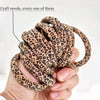 A hand holds a bundle of leopard print elastic hair ties for ponytails.