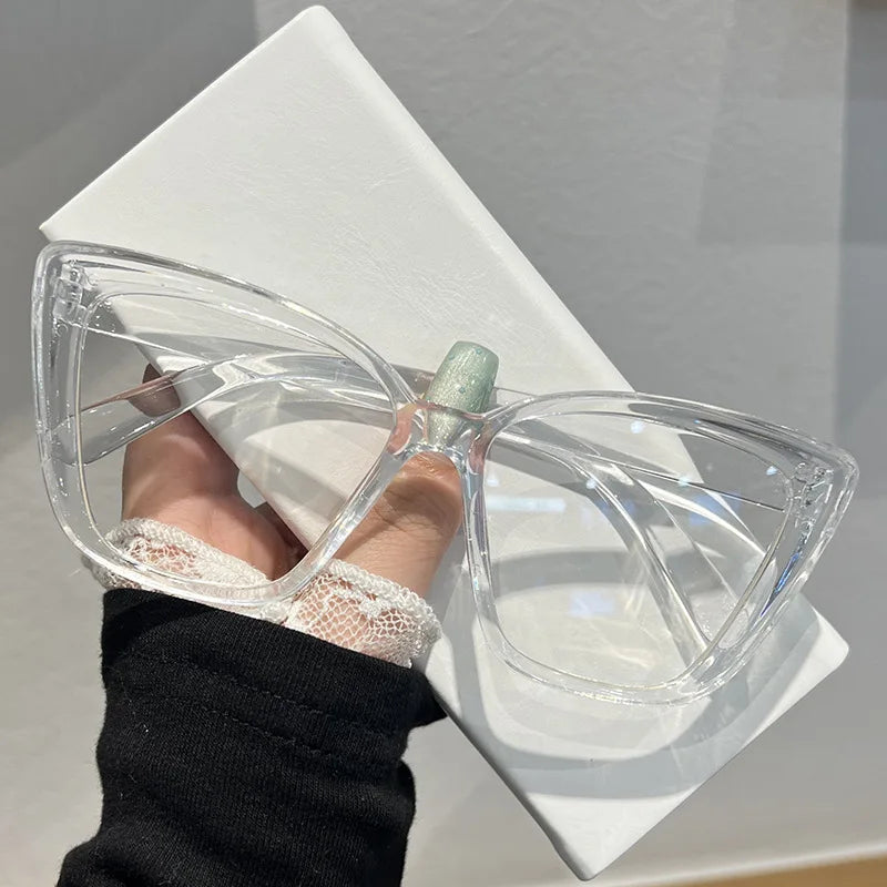 Clear acetate retro cat eye sunglasses resting on a white square display stand.