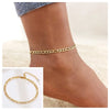 Gold stainless steel snake chain anklet worn on a woman's ankle.