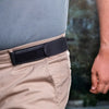 A close-up of a black elastic waist belt worn around the waistband of light tan pants.