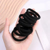 A hand holds a stack of black elastic hair bands for ponytail and hair ties.