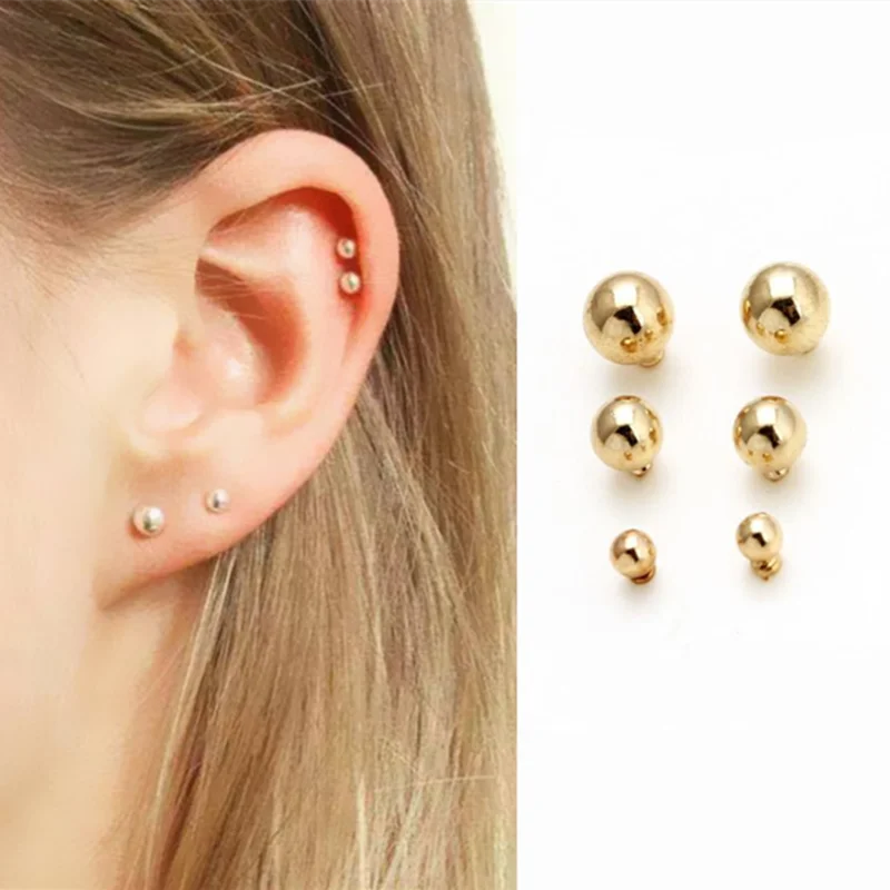 A close-up of a pair of gold-toned round stud earrings displayed on a white background.