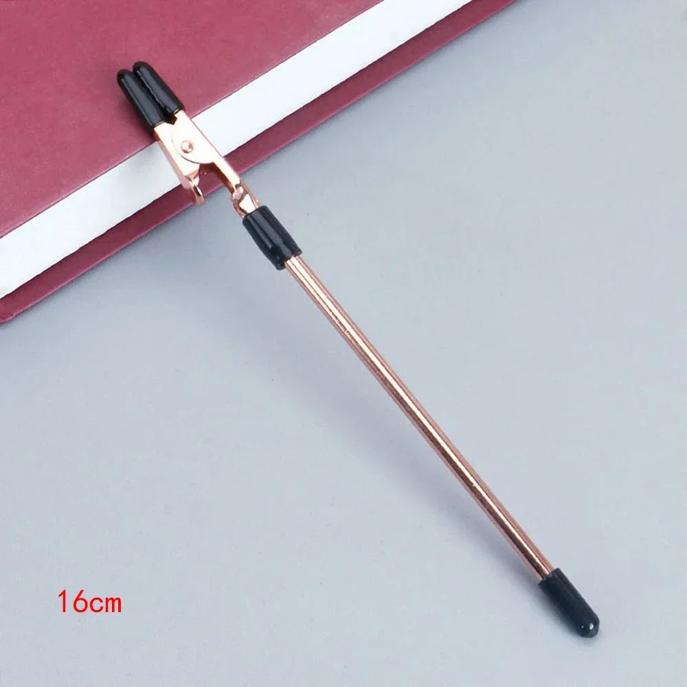 Pince de précision en or rose et noir posée sur un carnet rouge.