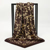 A dark brown and gold leopard print silk scarf draped over a black display stand.