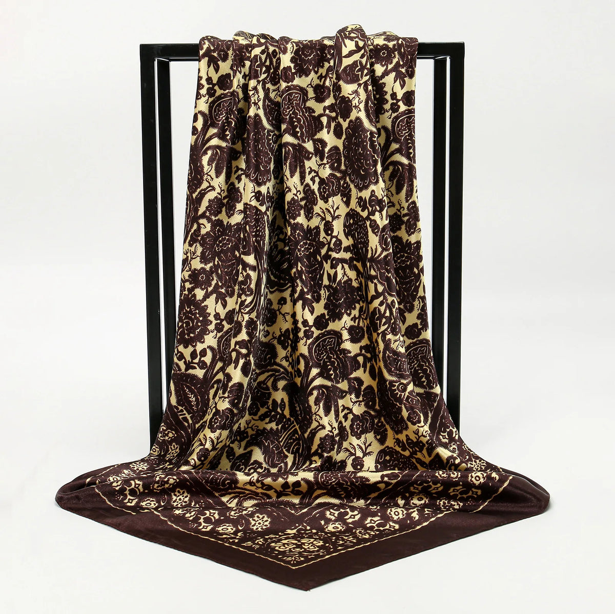 A dark brown and gold leopard print silk scarf draped over a black display stand.