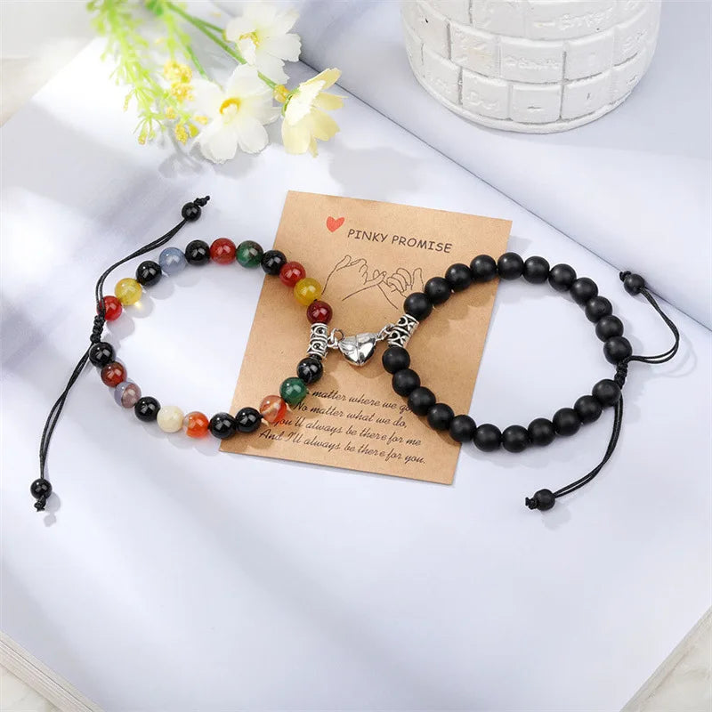 A set of natural stone heart couple bracelets featuring various colored stones and a silver heart charm on a brown card.