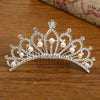 A sparkling crystal princess tiara hair comb for women with pearl accents resting on a wooden surface.