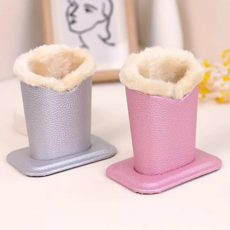 Ein Paar rosa Plüschbrillenhalter steht mit hellbeigen, flauschigen Oberteilen auf einer weißen Oberfläche.