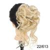 A close-up of a blonde hairpiece styled in a voluminous, messy bun on a dark background.