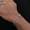 A close-up of a man's wrist wearing a silver stainless steel Cuban link bracelet.