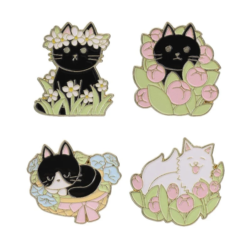 A set of enamel flower brooches featuring black cats and white cats surrounded by pink and green flowers.
