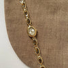Montre-bracelet en quartz ton or avec cadran ovale et bracelet maillons sur fond de tissu marron.