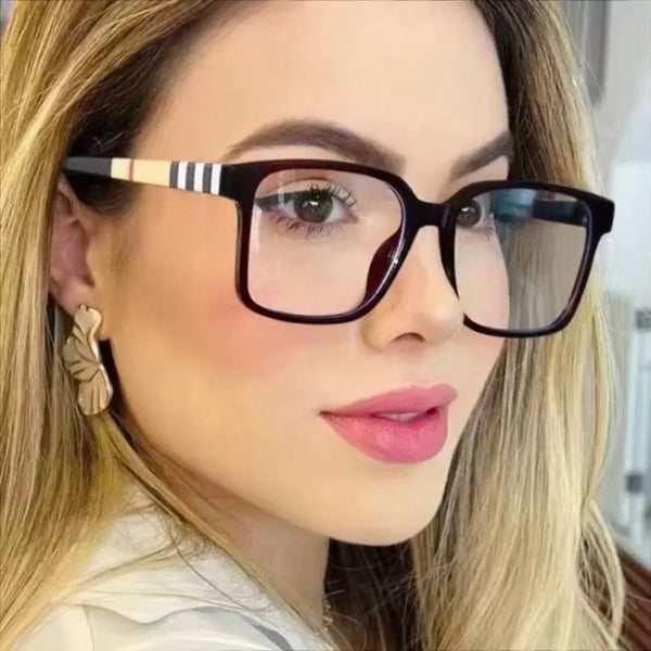 امرأة ترتدي نظارات شمسية سوداء بتصميم قديم بإطارات مخططة وشعر بني فاتح.
