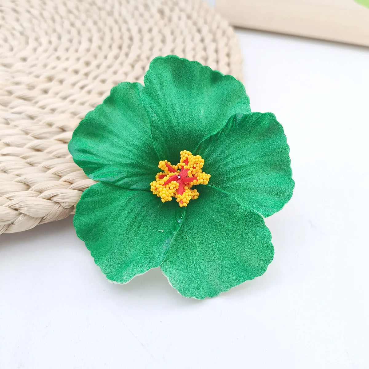 A vibrant green fabric flower with a yellow center rests on a beige woven mat.