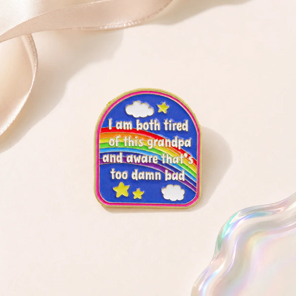 A colorful enamel pin featuring clouds and stars with the text I am both tired of this grandpa and aware that's too damn bad
