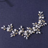 A delicate bridal hairband made of small white and cream pearls and gold-toned leaves.