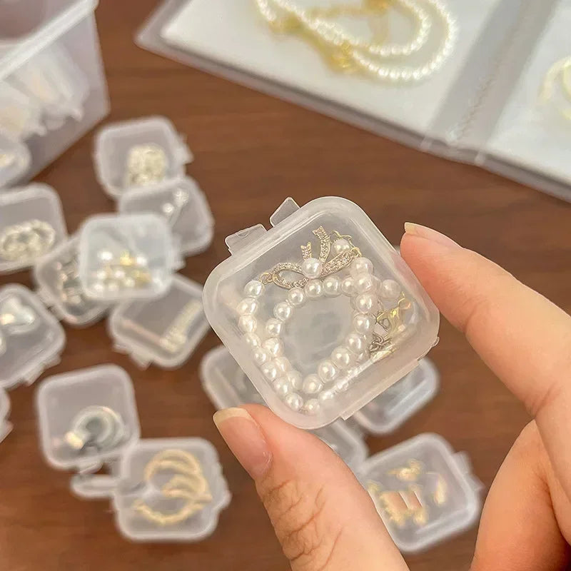 Eine Hand hält eine durchsichtige Plastikbox, gefüllt mit goldfarbener Perlen- und Diamant-Schmuckware.