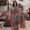 A woman models an orange and black leopard zebra print maxi kaftan outdoors in a garden setting.