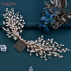 A delicate bridal headpiece made of gold-toned wire adorned with clear rhinestones and small leaves, resting on a dark teal s