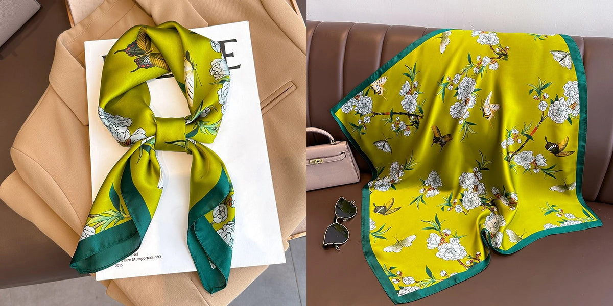 A bright yellow silk scarf with a floral print and green trim is displayed on a brown leather sofa.