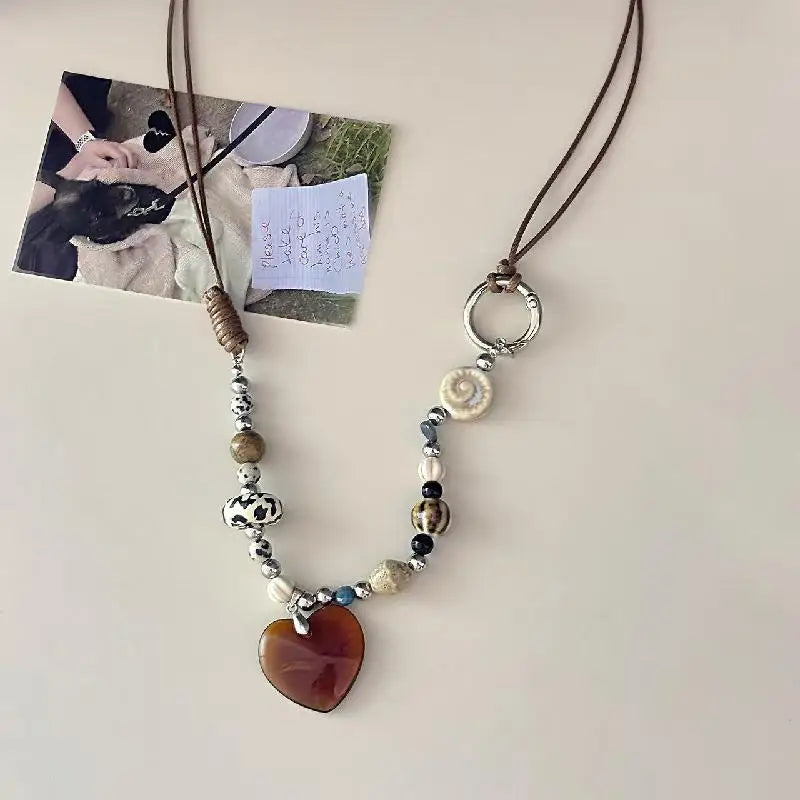 A beaded pendant necklace featuring various stones and beads on a dark brown leather cord.