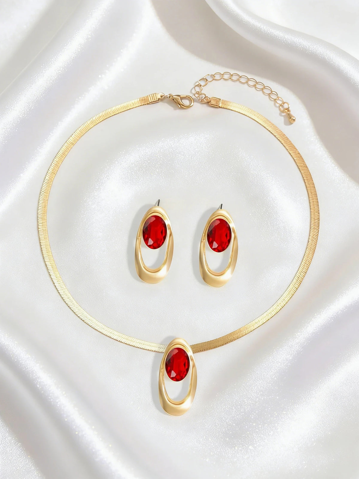 Gold necklace set featuring a thin chain and three oval red gemstone pendant earrings