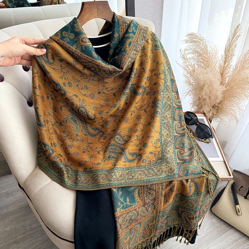 A close-up of a brown and teal bohemian paisley tassel shawl draped over a person's shoulder.