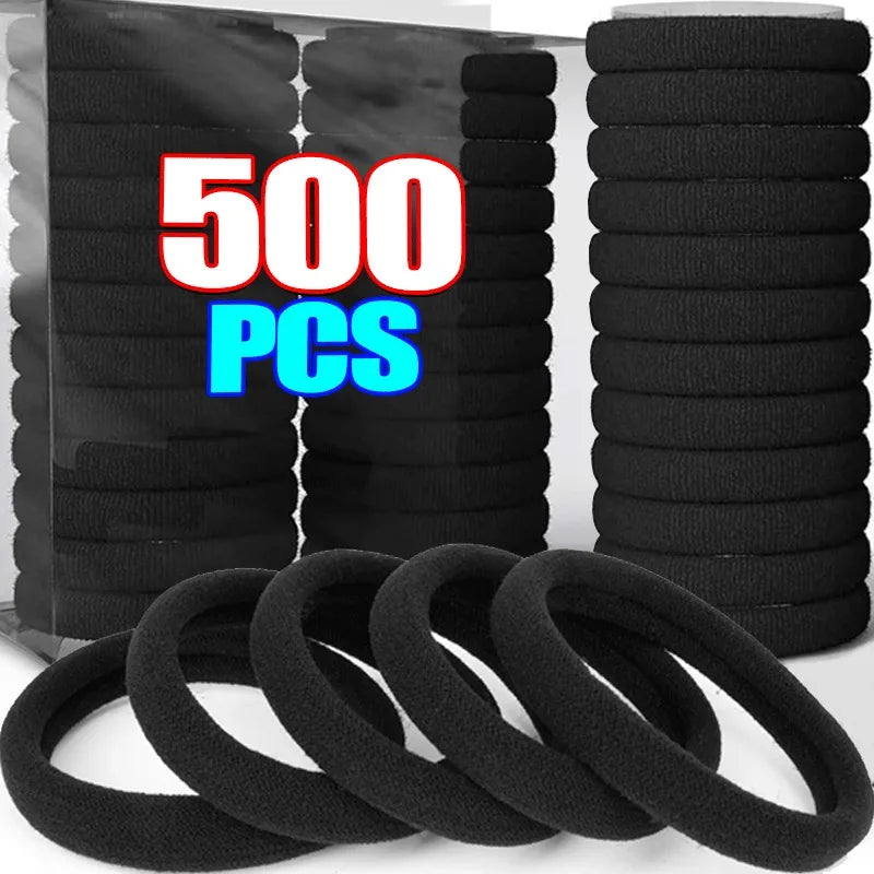 A stack of black elastic hair bands and several loose black hair ties.