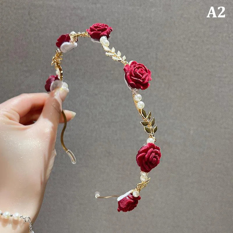 A close-up of an elegant rose vine headband hair accessory featuring deep red roses and pearl accents.