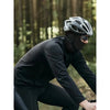 Une personne portant un cache-col tactique noir et des lunettes dans une forêt.