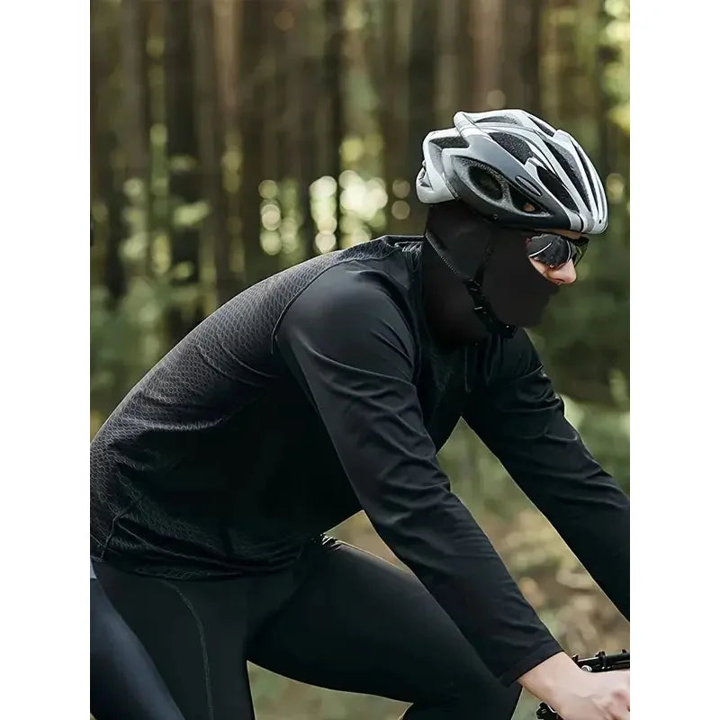 Une personne portant un cache-col tactique noir et des lunettes dans une forêt.