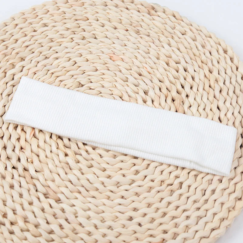 A white knitted elastic headband lying on a natural woven mat.