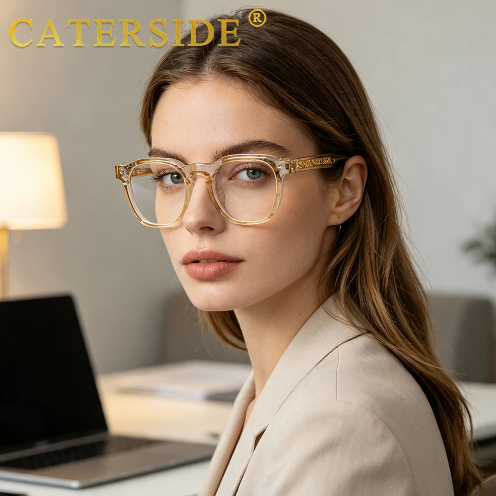 A close-up of a woman wearing gold-rimmed retro square anti-blue light eyeglasses in a professional setting.
