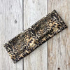Diadema deportiva impermeable de leopardo negro y caqui sobre una superficie de madera clara.