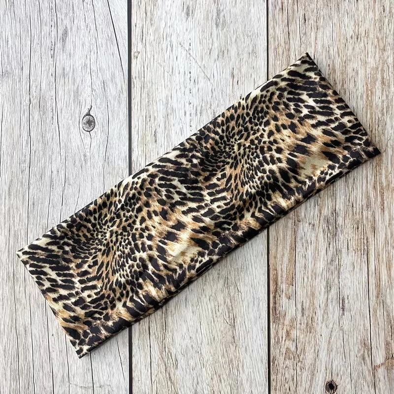 Diadema deportiva impermeable de leopardo negro y caqui sobre una superficie de madera clara.