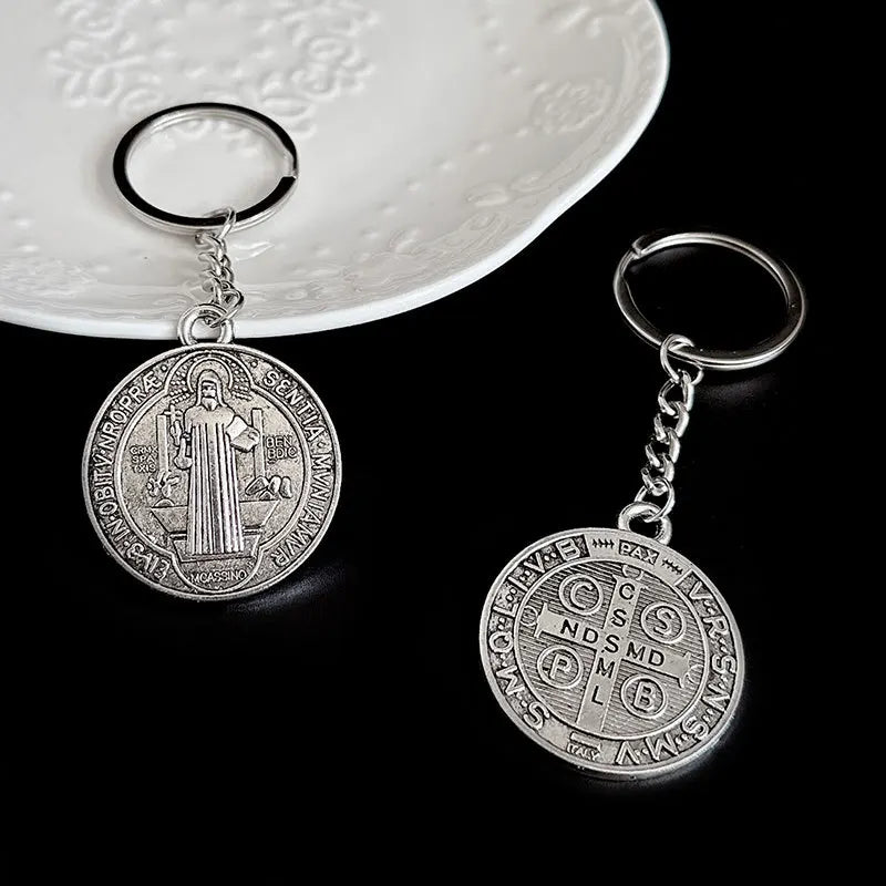 Silver round medallion keychain featuring a depiction of Saint Benedict.