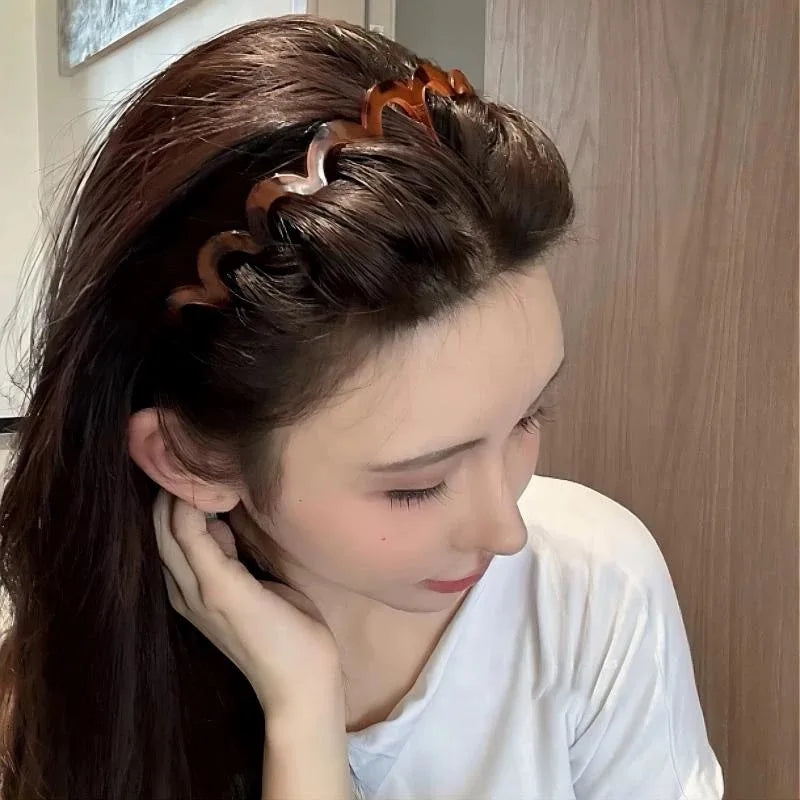 A woman with long dark hair wears a brown resin wave toothed headband styled in an updo.