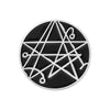 A black enamel pin featuring a geometric, star-like design with white lines.