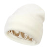 A cream-colored beanie hat with a satin lining shown from the side.