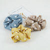 Three knitted hair scrunchie headbands in blue, beige, and yellow are displayed on a white background.