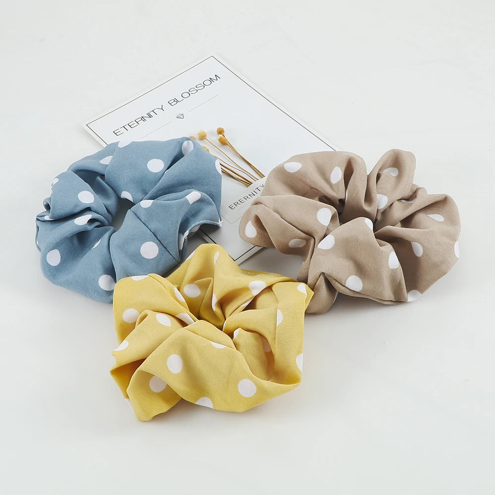 Three knitted hair scrunchie headbands in blue, beige, and yellow are displayed on a white background.